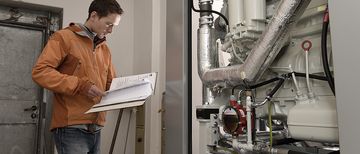 Heizzentrale Wärme- und Energielösugen Ingenieur von NaturEnergie betrachtet Baupläne in einer Heizzentrale, Wärme- und Energielösungen