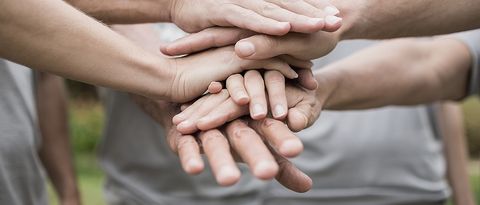 Hände liegen übereinander Hände eines mehrköpfigen Teams mit heller Kleidung liegen aufeinander. Teamzusammenhalt soll ausgedrückt werden.