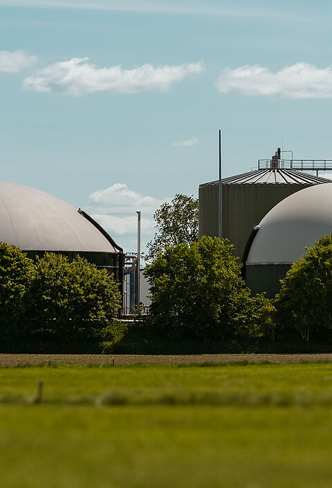 Biogasanlage mit mehreren Kuppeln in grüner Landschaft