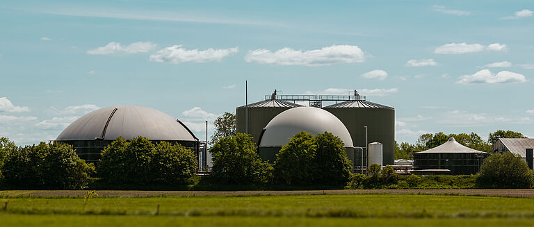 Biogasanlage mit mehreren Kuppeln in grüner Landschaft