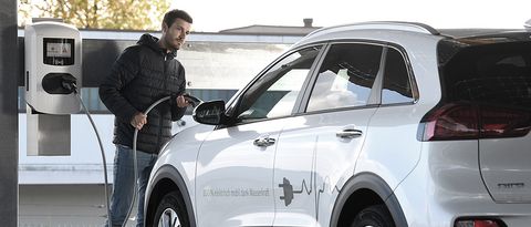 Ein Autofahrer lädt gerade sein weißes Elektrofahrzeug an einer Ladestation von NaturEnergie auf. 