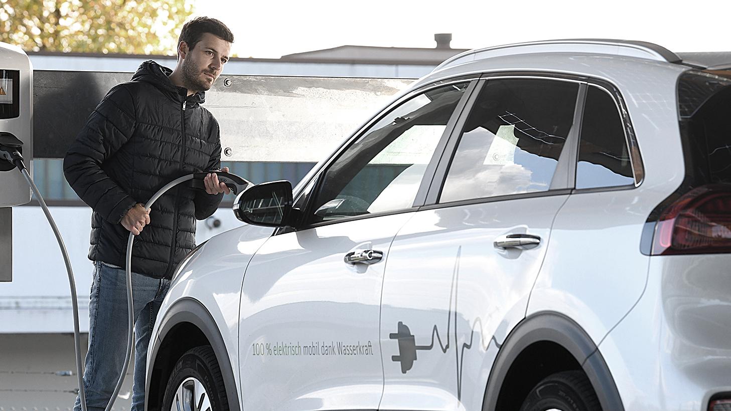 Ein Autofahrer lädt gerade sein weißes Elektrofahrzeug an einer Ladestation von NaturEnergie auf. 