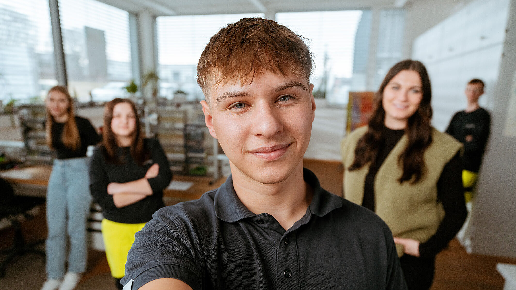 Gruppe von Mitarbeitenden in einem hellen Büro, vorne eine Person mit naturenergie‑Logo auf dem Shirt.