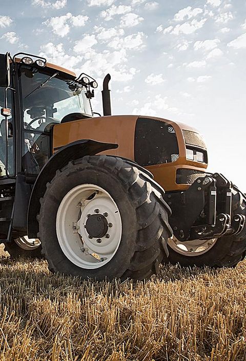 Ein Traktor mit Anhänger steht auf einem Feld bei schönem Wetter und blauem Himmel