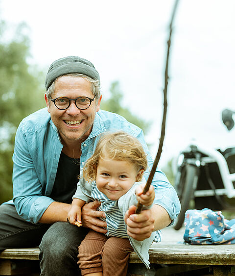 Ein Papa macht mit seiner Tochter einen Ausflug in die Natur und angelt