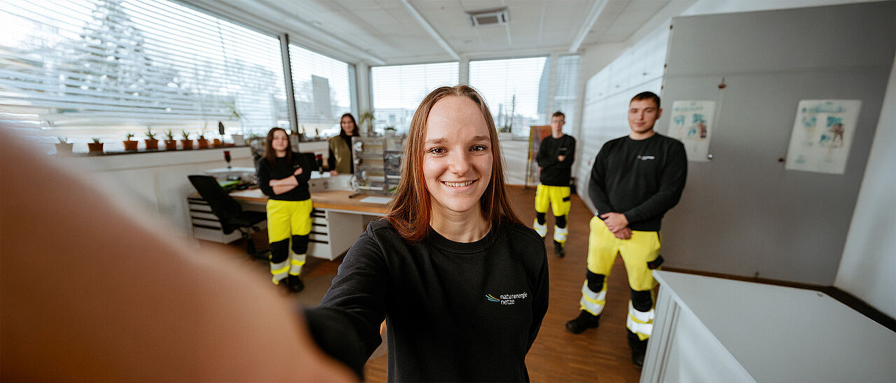 Mehrere Personen stehen in einem Technikraum mit Werkbänken und technischen Geräten.