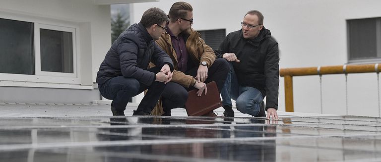 NaturEnergie Solar-Team auf dem PV-Dach, diskutiert über die Solaranlage