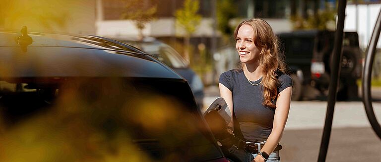 Elektroauto wird geladen im urbanen Umfeld Person lädt Elektroauto in städtischer Umgebung mit Ladekabel