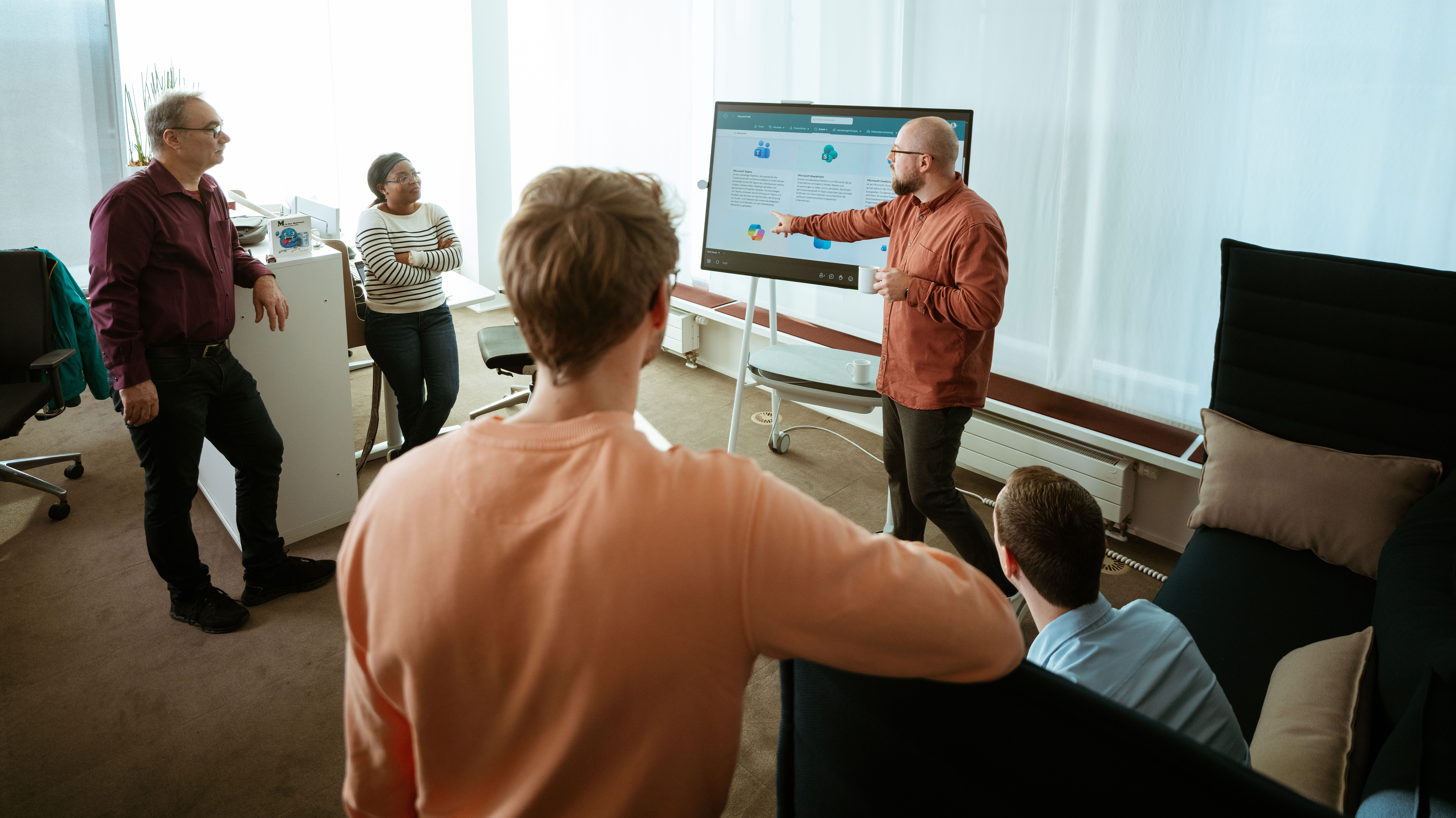 naturenergie Standort Südbaden. Ein Mitarbeiter präsentiert Inhalte auf einem Bildschirm, während mehrere Kolleginnen und Kollegen in einem hellen Büro zuhören.