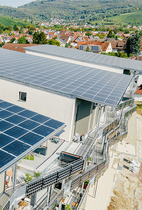 Gebäude mit Solarpanelen auf den Dächern in hügeliger Landschaft