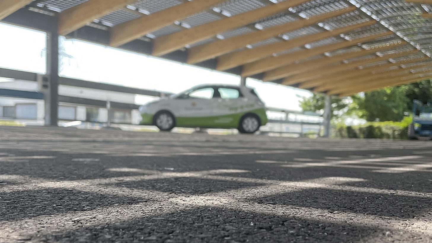Schattenspiel auf Asphaltboden, im Hintergrund steht ein my-e-car unter einem Photovoltaikdach