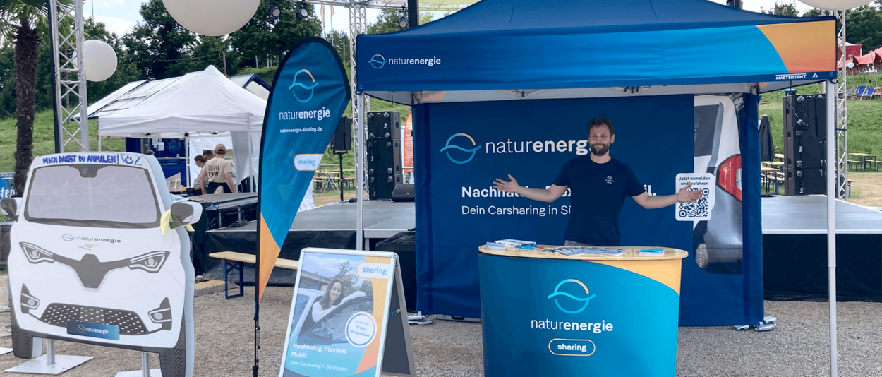 Infostand von naturenergie im Freien mit Pavillon, Infotisch und Auto-Aufsteller