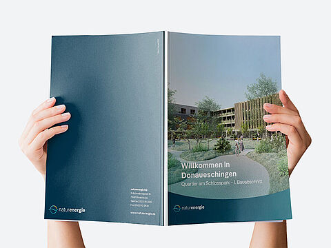  Aufgeschlagene Broschüre mit Wohngebäude und naturenergie-Kontaktinformationen