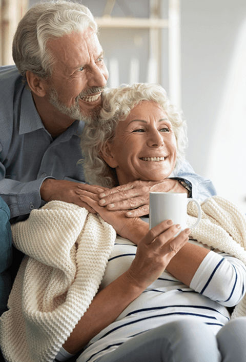 Ein glücklicher, liebevoller Rentner, der sich um die lächelnde Frau mittleren Alters kümmert und sie mit einer Decke bedeckt und gemeinsam von der Zukunft träumt. liebevolles Ehepaar mit süßem, zartem, gemütlichem Moment.