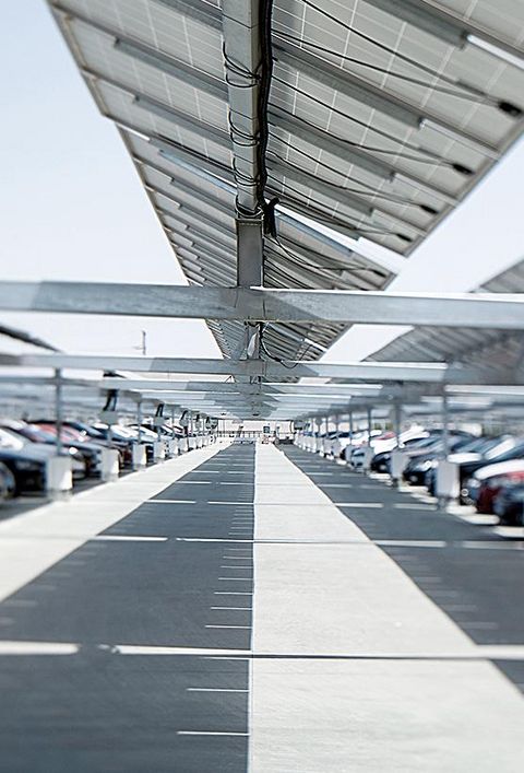 Ein großer Parkplatz mit Autos unter einem PV-Carport 