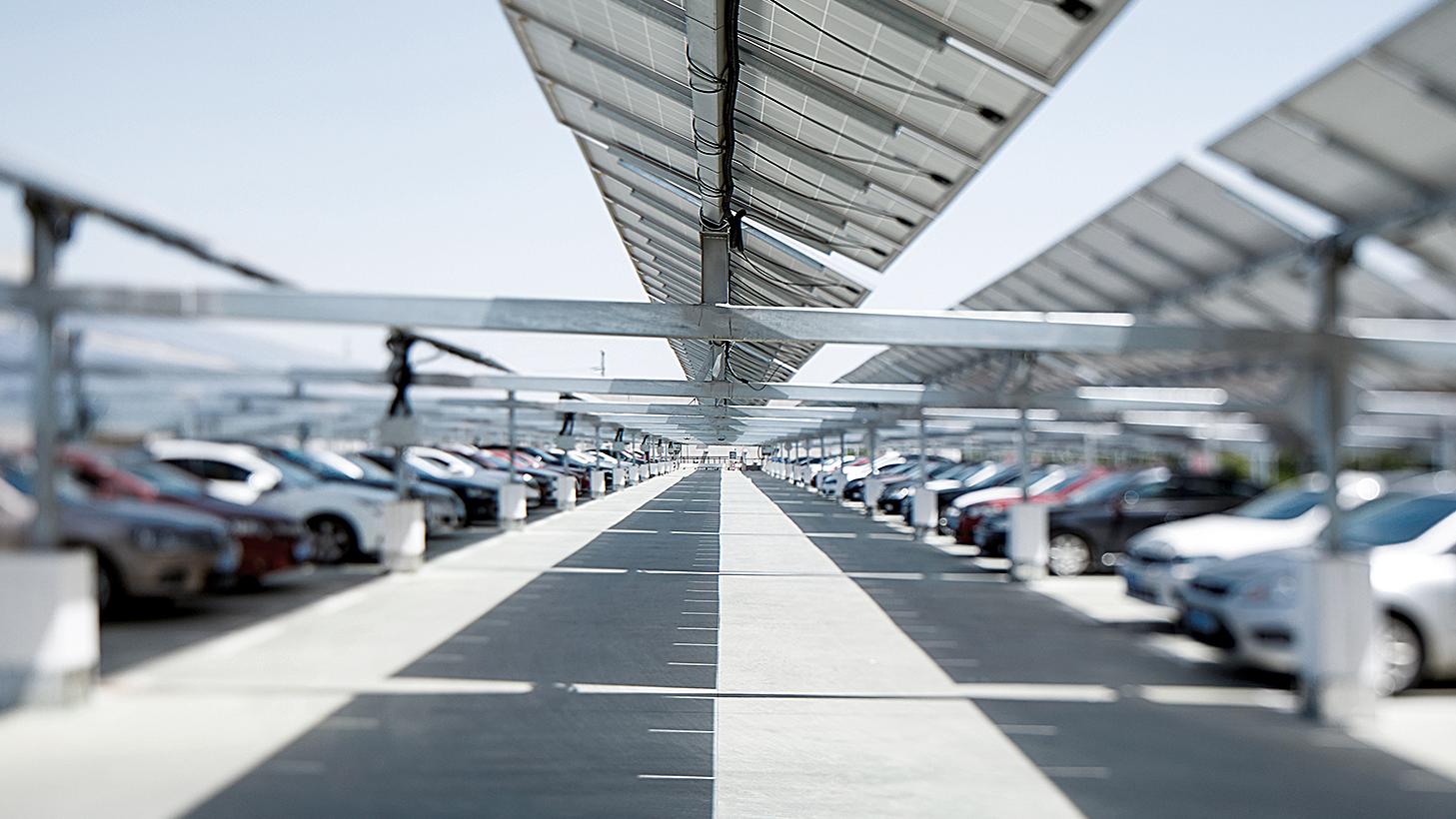 Ein großer Parkplatz mit Autos unter einem PV-Carport 