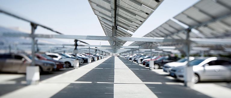 Ein großer Parkplatz mit Autos unter einem PV-Carport 