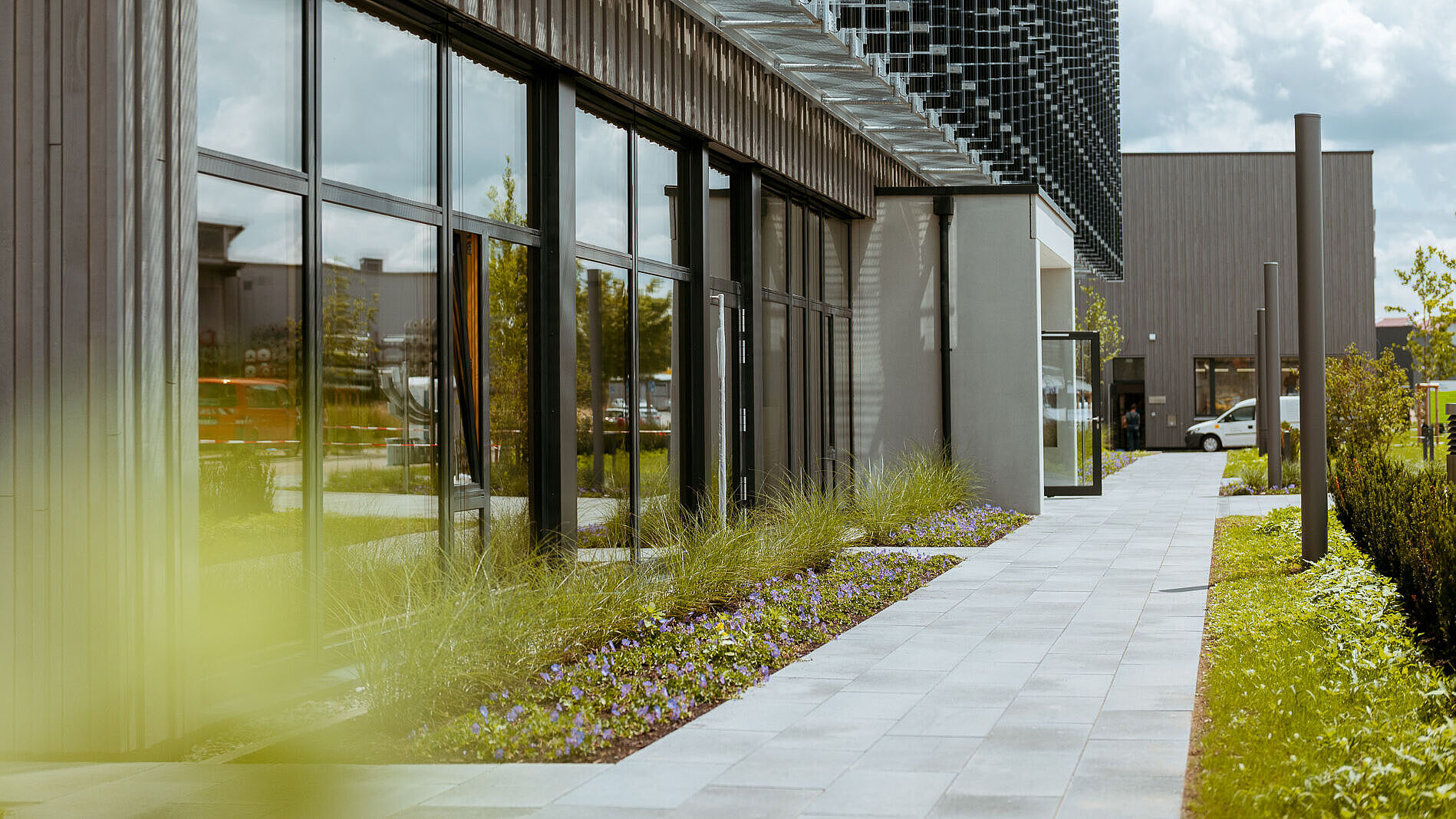 naturenergie Standort Südbaden. Moderner Bürogebäudekomplex mit Glasfassade, Gehweg und bepflanztem Außenbereich.