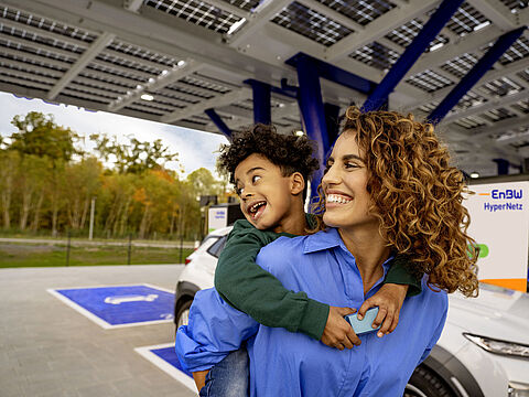 Ein Bild mit einer Frau und ihrem Kind vor einem EnBW Ladepunkt für e-Autos