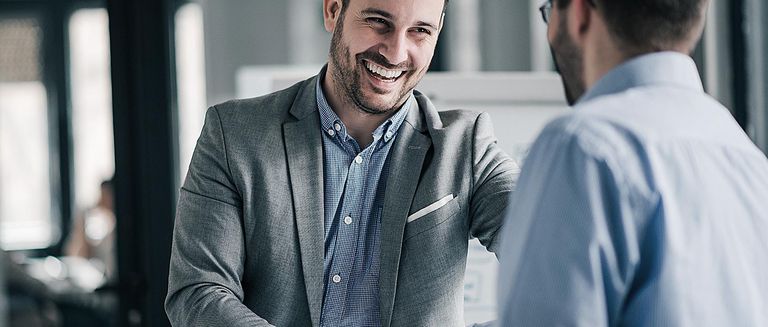 Zwei glückliche, professionelle Geschäftsleute, die sich nach erfolgreichem Abschluss im Büro die Hand geben. 