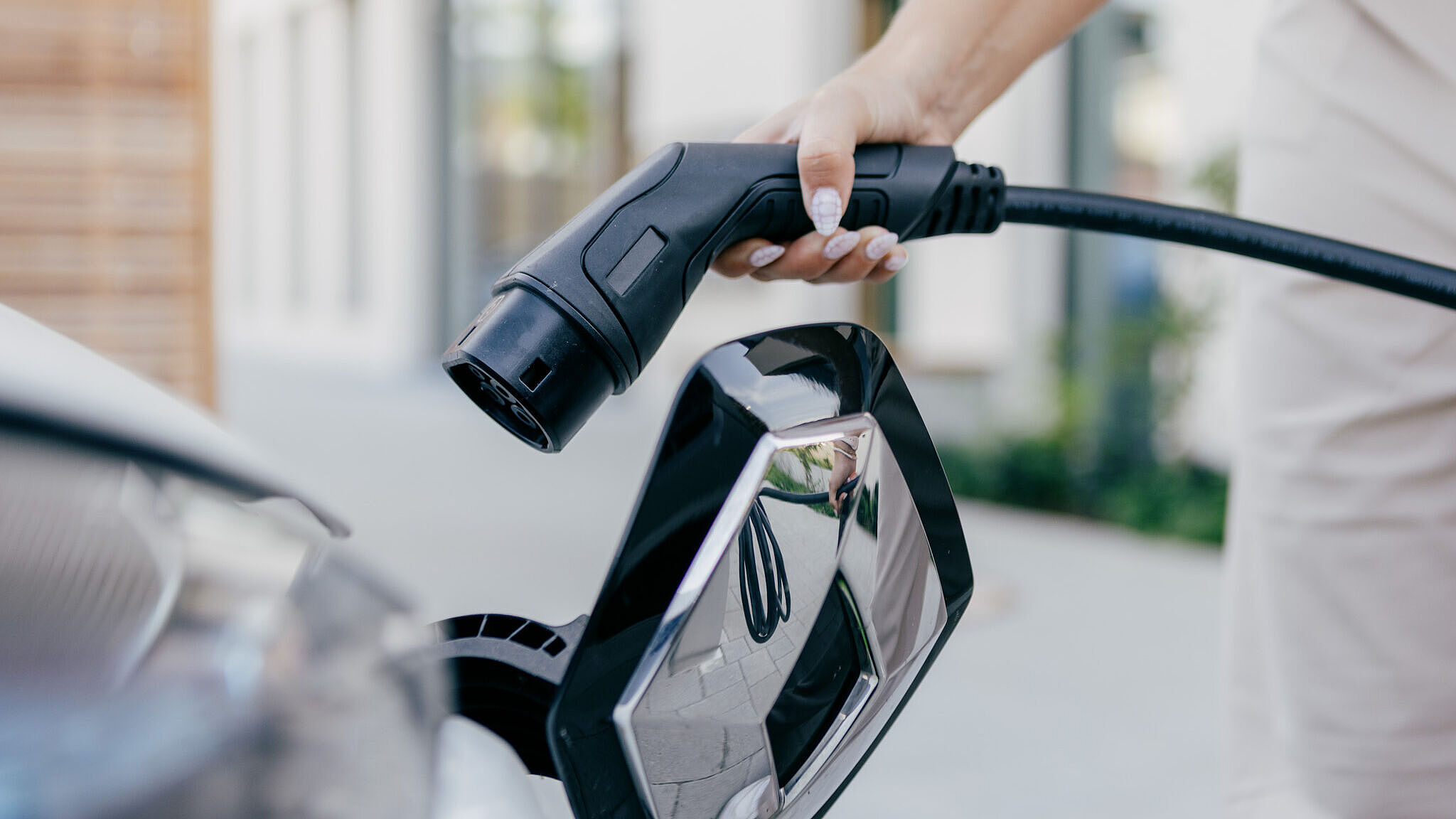 Eine Person schließt ein Ladekabel an ein Elektroauto an.