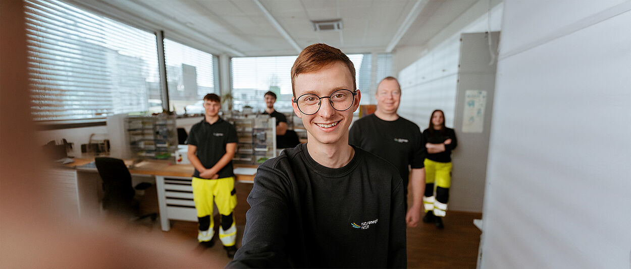 Mehrere Personen stehen in einem Technikraum mit Werkbänken und technischen Geräten.