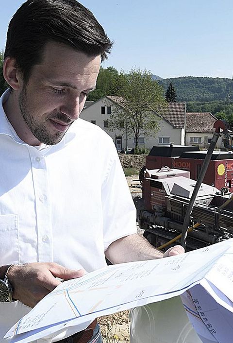 Nahwärme in Murg, Ingenieur von NaturEnergie betrachtet Baupläne auf der Baustelle bei sonnigem Wetter 