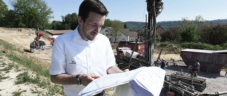 Nahwärme in Murg, Ingenieur von NaturEnergie betrachtet Baupläne auf der Baustelle bei sonnigem Wetter 