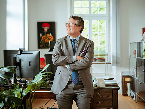 Dr. Tobias Benz, Bürgermeister von Grenzach-Wyhlen, steht mit verschränkten Armen in seinem Büro.