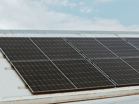 Solarpaneele auf schrägem Hausdach Dach mit installierten Solarpaneelen unter einem teilweise bewölkten Himmel.