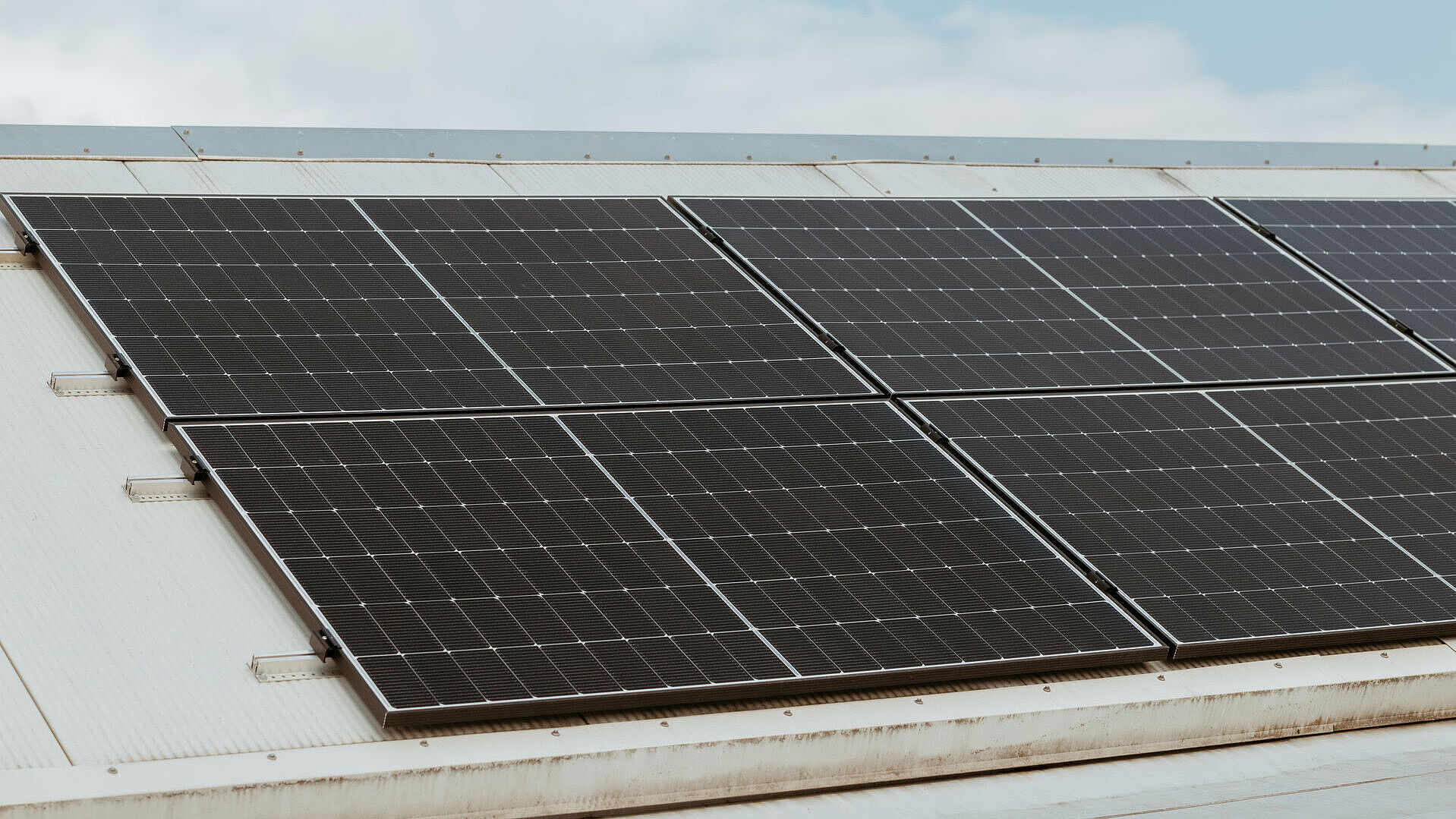 Dach mit installierten Solarpaneelen unter einem teilweise bewölkten Himmel.