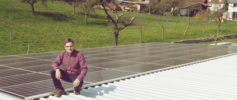 Referenzbild eines NaturEnergie Photovoltaik-Kunden. Geschäftsführer eines KMUs neben der PV-Anlage