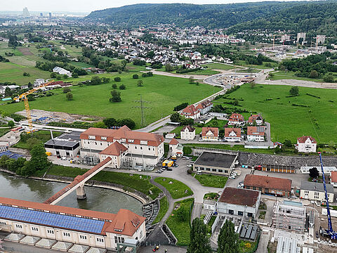 Luftaufnahme des Nahwärmekraftwerks in Wyhlen mit umliegenden Gebäuden und Grünflächen.