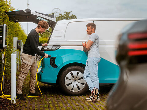 Elektro-Transporter wird an einer Ladesäule auf einem Parkplatz geladen.