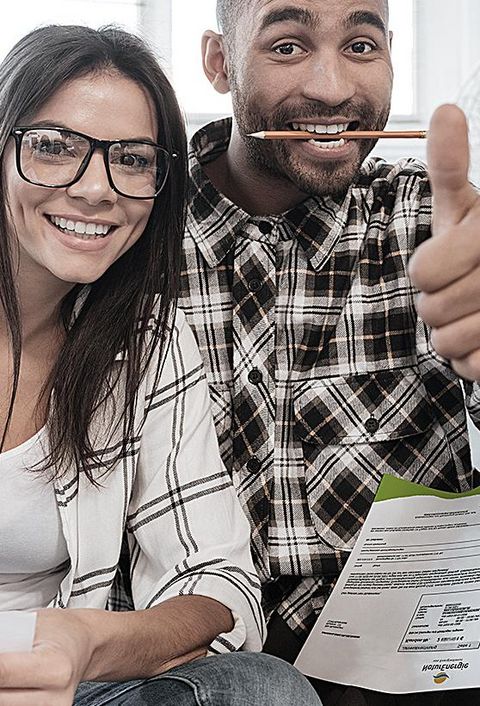 Foto von glücklichen Kunden daheim, die mit Dokumenten auf dem Boden arbeiten. Schauen Sie sich die Kamera an, während Sie die Daumen nach oben ziehen.