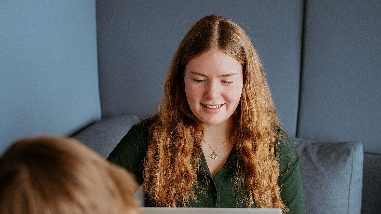 Zwei Personen arbeiten gemeinsam an einem Tisch mit Laptop und Tablet.