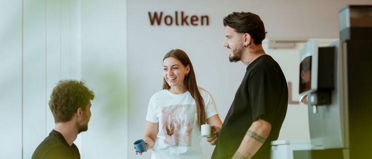 Das Bild zeigt drei Personen, die in der Kaffeeküche am Standort in Rheinfelden stehen und sich unterhalten.