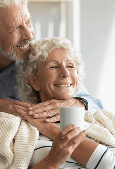 Ein glücklicher, liebevoller Rentner, der sich um die lächelnde Frau mittleren Alters kümmert und sie mit einer Decke bedeckt und gemeinsam von der Zukunft träumt. liebevolles Ehepaar mit süßem, zartem, gemütlichem Moment.