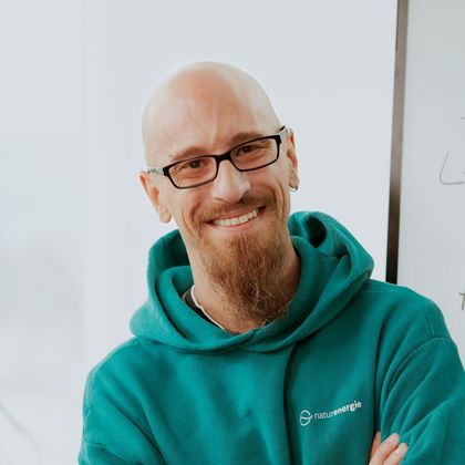 Daniel Albiez, IT Support Specialist, steht mit verschränkten Armen vor einem Whiteboard